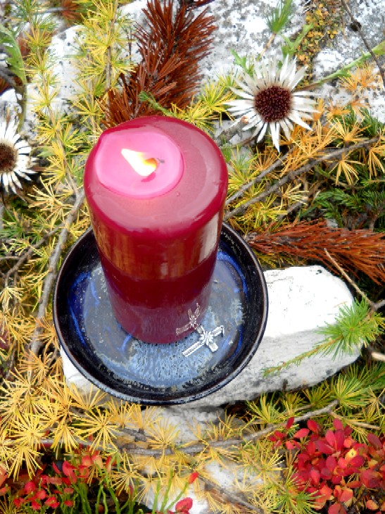 Foto: ein zu verschenkendes Edelweiß-Berg-Kreuz liegt zur Segnung auf dem Altar bei der Kerze
