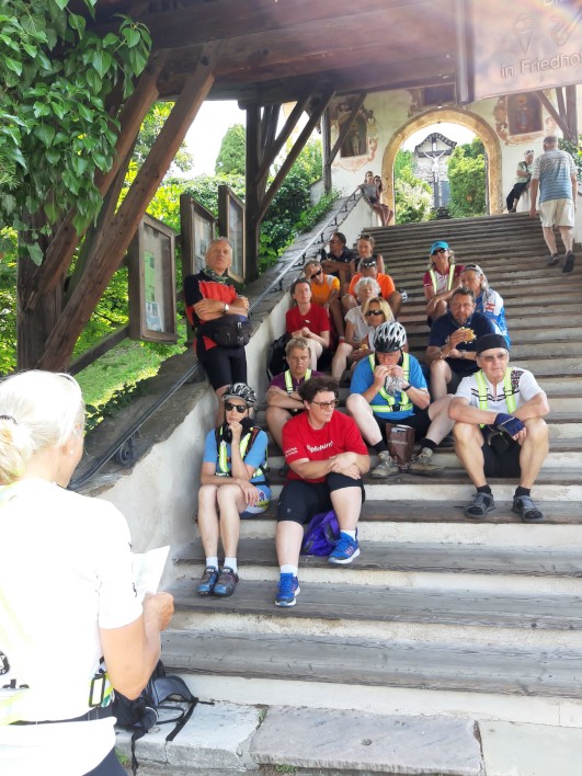 Hochformat-Foto vom 23.07.2021 Gruppe lauscht aufmerksam auf einer Treppe bei Maria Wörth